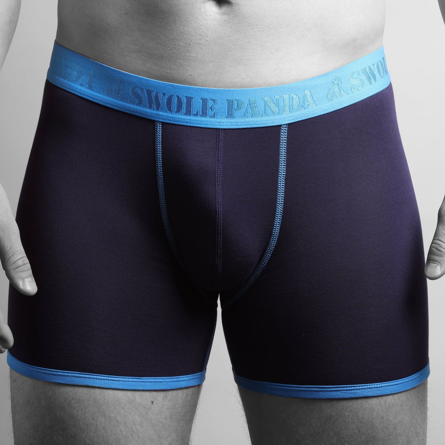 A pair of navy blue bamboo boxer briefs with a blue waistband, displayed on a model.