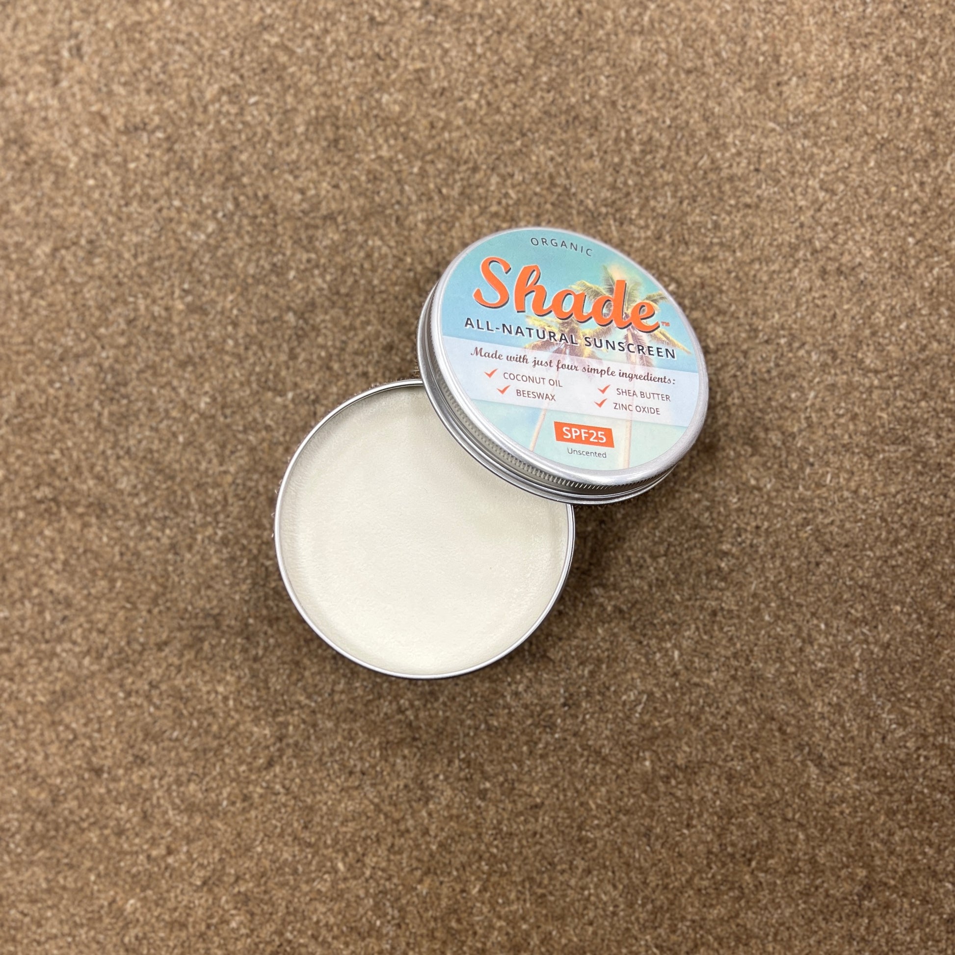 Tin sat on wooden background, lid off showing white cream inside the tin