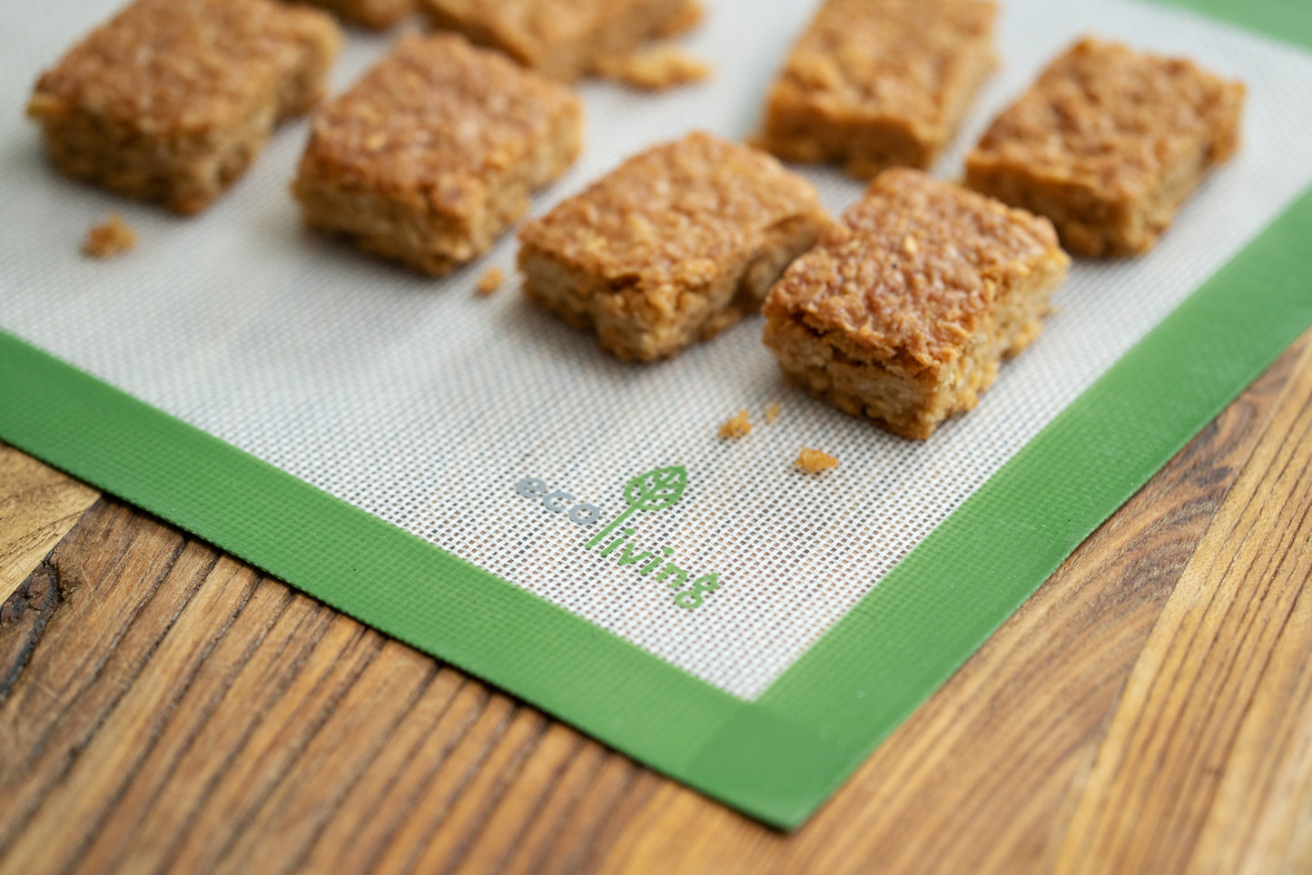 Ecoliving Silicone Baking Liner laid flat on a wooden surface, with flapjacks on top of it.