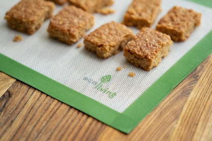 Ecoliving Silicone Baking Liner laid flat on a wooden surface, with flapjacks on top of it.