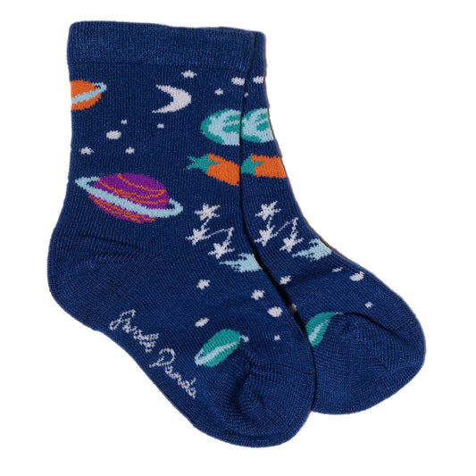 Swole Panda Kids Outer Space socks that show planets, constellations, and moon and shooting stars. The stars and moon are white, while the planets range from turquoise blue, to purple with a stripe and bright orange. They all sit on a dark blue background, and Swole Panda is written on the sole of the socks in cursive. The socks are laid on a white background.