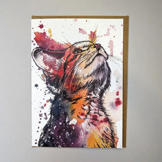 Tori Ratcliffe Art watercolour and pen drawing of a kitten. The kitten is looking up to the right top corner of the card and is coloured with patches and blends of purples, pinks, very dark blues and yellows. The card has the edge of a brown envelope sticking out the right side and it is placed on a white background.