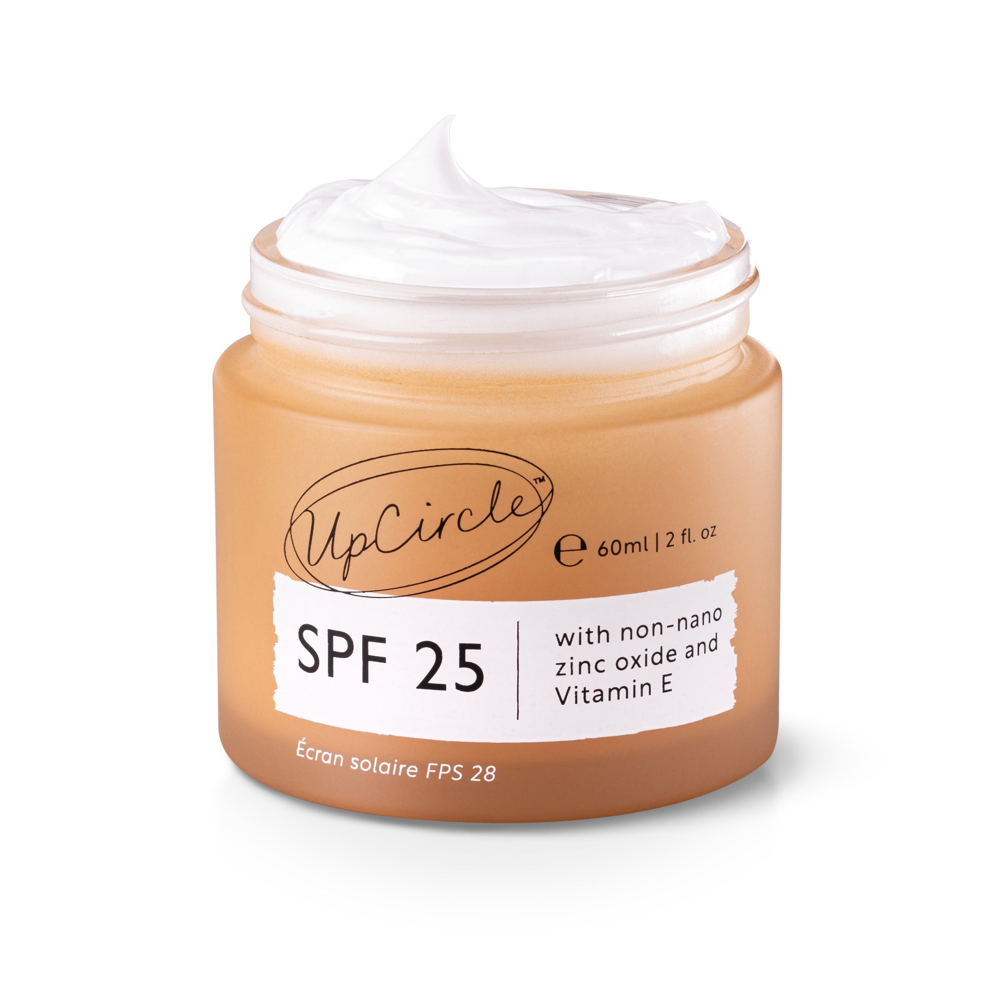 A peachy jar of UpCircle SPF25 Mineral Sunscreen, with a white strip across the front detailing “zinc oxide and vitamin E”. The sunscreen is whipped slightly and is coming out the top of the open jar. The jar is on a white background.